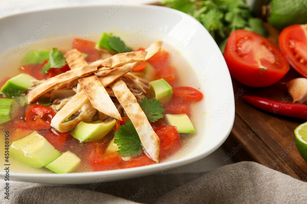 Bowl of tasty Sopa de Lima soup and ingredients on table