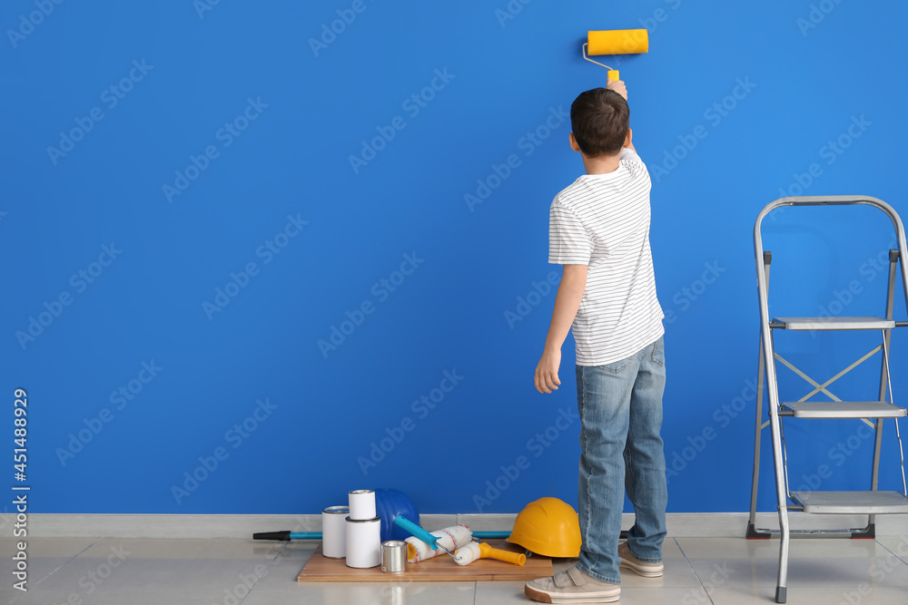 Little boy painting wall in room