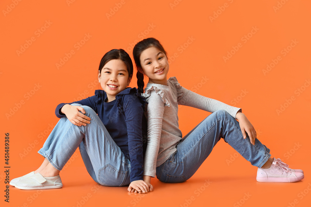 Cute little sisters on color background