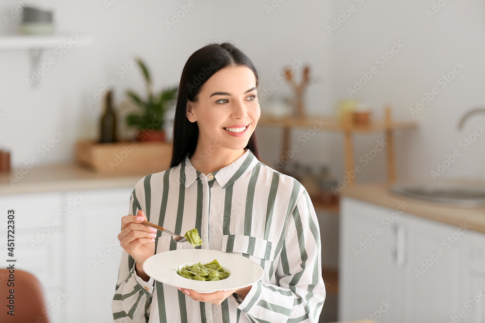 漂亮的年轻女人在家吃美味的饺子