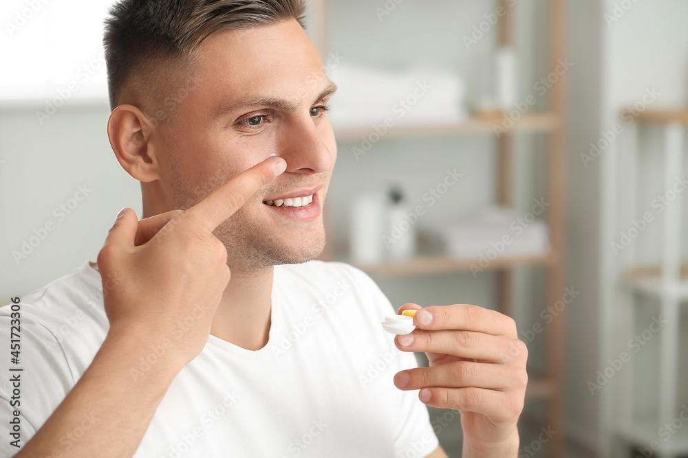 Young man putting in contact lenses at home