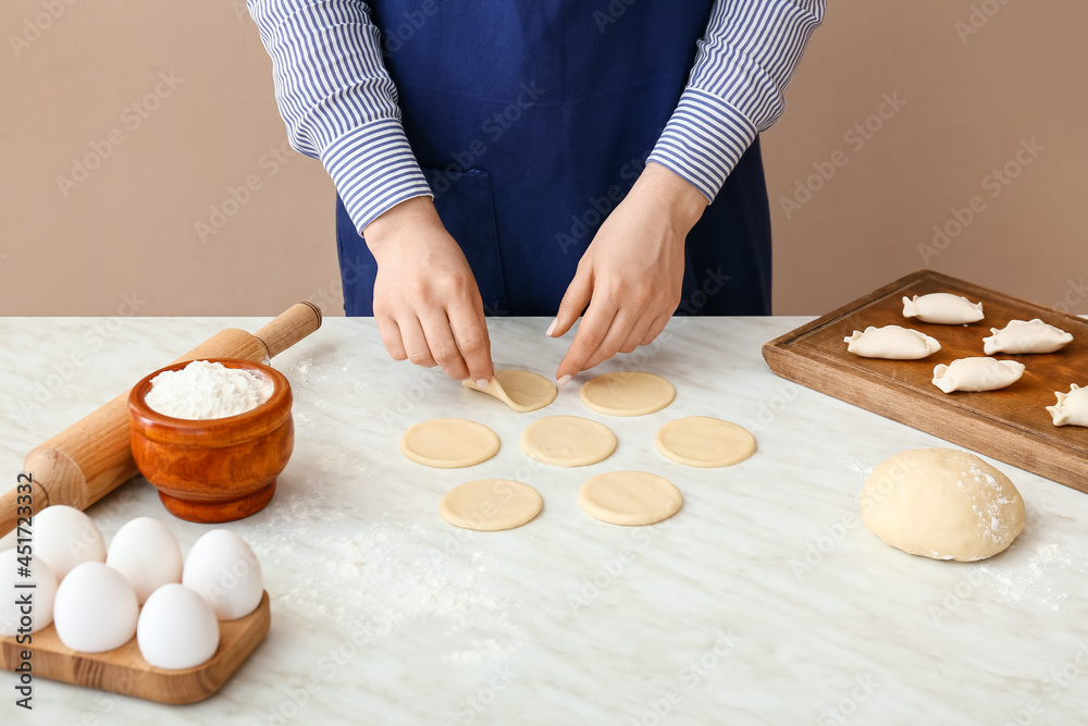 Woman preparing tasty dumplings on table in kitchen, closeup