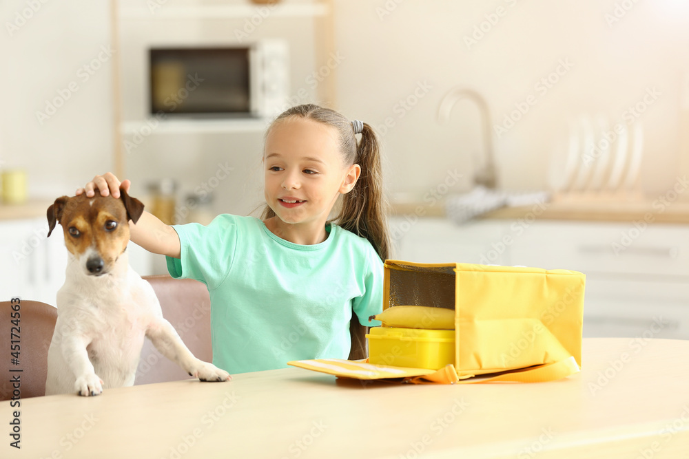 Cute little girl with funny dog putting her lunch in bag