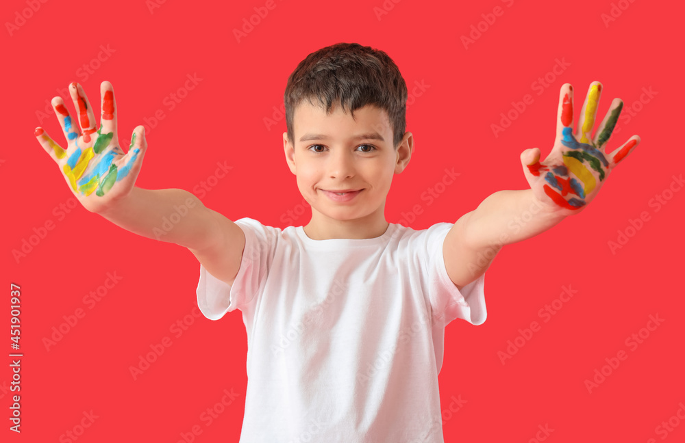 Little boy with hands in paint on color background