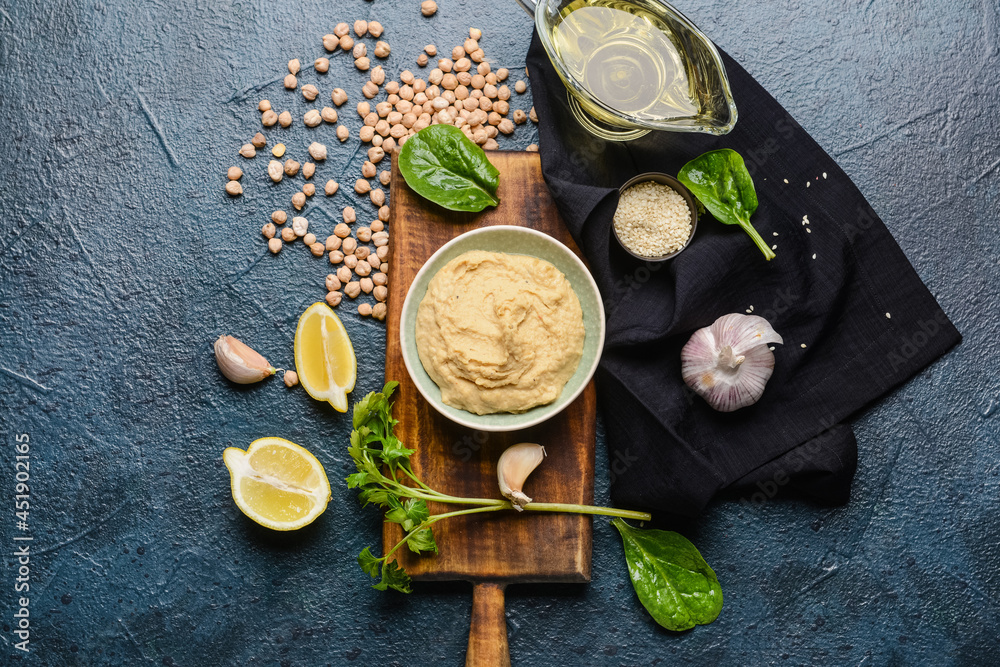 Composition with tasty hummus and ingredients on dark background