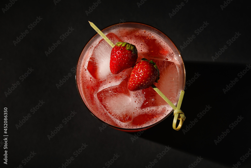 Glass of tasty strawberry margarita on dark background