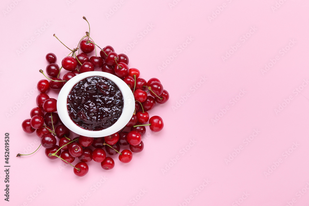 Bowl with tasty cherry jam on color background