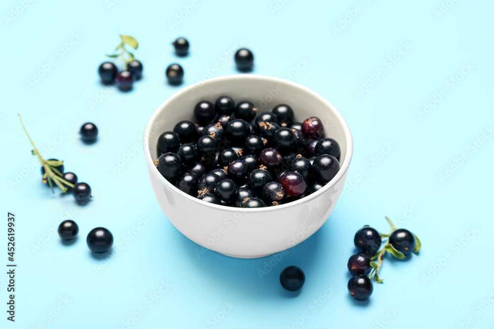 Bowl with ripe black currant on color background