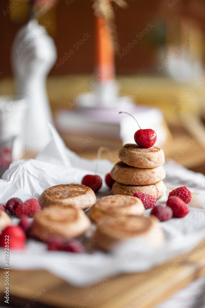 Cheesecakes decorated with cherry on a parchment paper on the table. Sweet home made dessert or brea