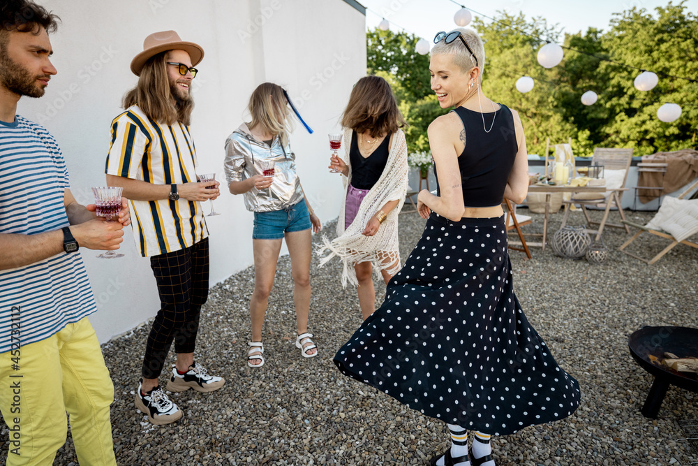 Young stylish friends dancing and having fun at party on the rooftop terrace. Fun and active spendin