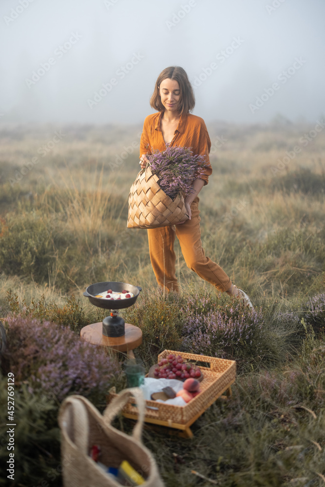 一个可爱的女人的肖像，手里拿着刚摘下的石南花花束，在公园里吃早餐野餐