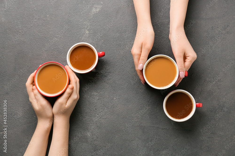 Female hands and cups of coffee on dark background