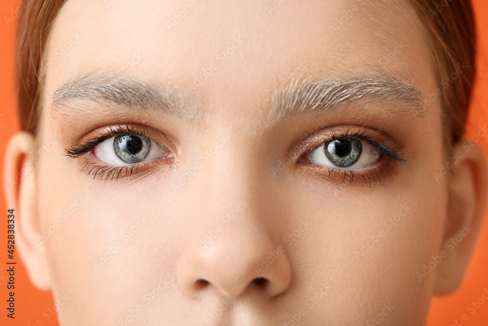 Beautiful young woman with dyed eyebrows on color background, closeup