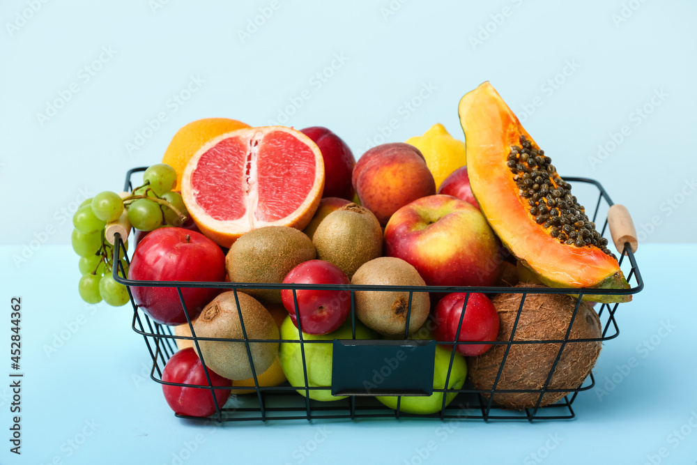 Basket with fresh fruits on color background