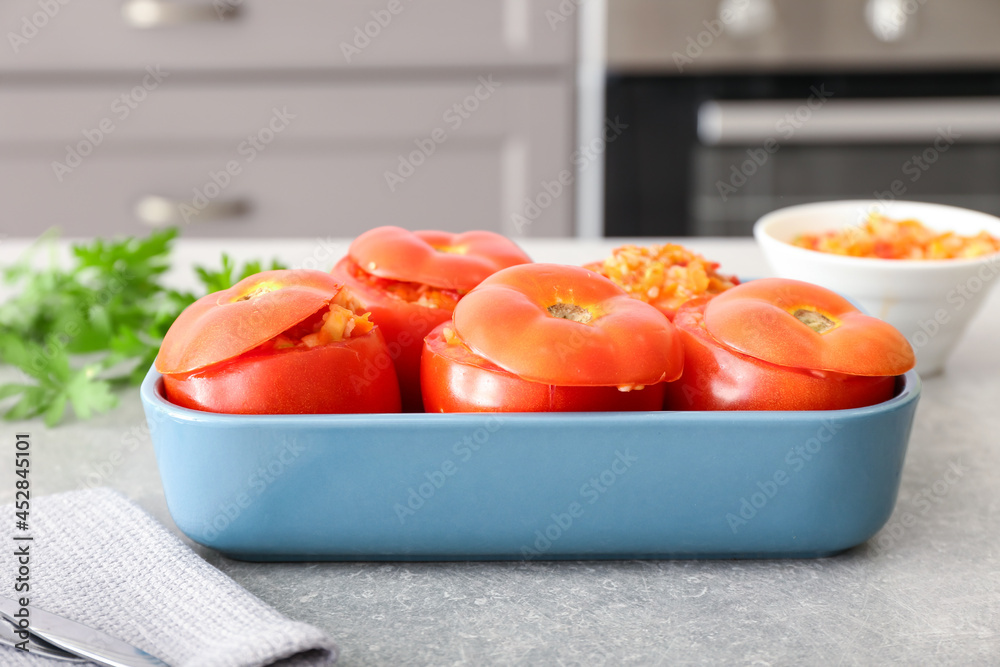 Baking dish with stuffed tomatoes on table in kitchen