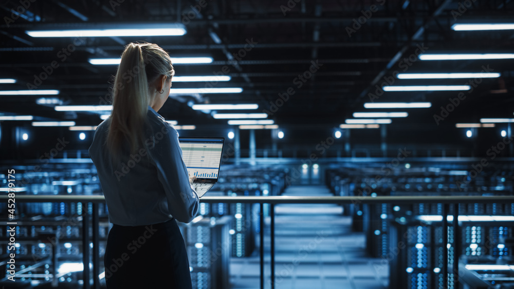 Data Center Female IT Specialist Uses Laptop Computer. Cloud Computing Server Farm with IT Engineer 