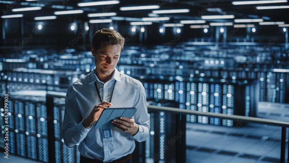 Portrait of Smiling IT Specialist Using Tablet Computer in Data Center. Big Server Farm Cloud Comput