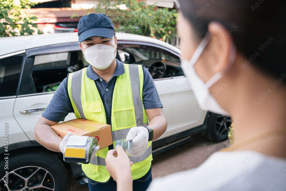 Asian delivery man accept credit card using a credit card reader while delivering products to custom