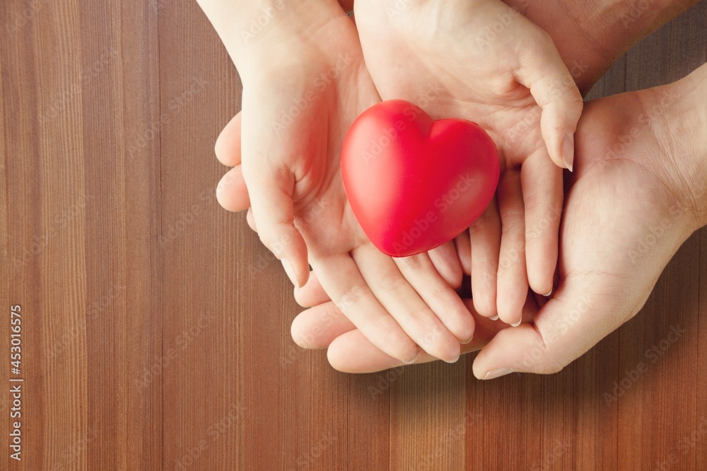 Man and woman holding red heart on background