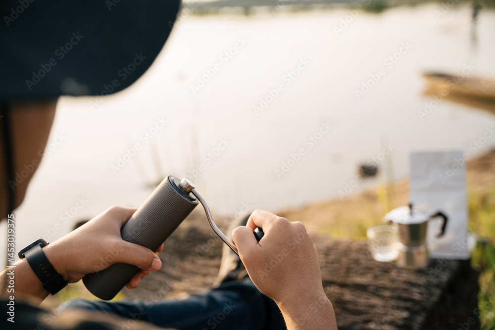 A hand holding stainless steel grinder for grinding coffee beans with manual to make black coffee en