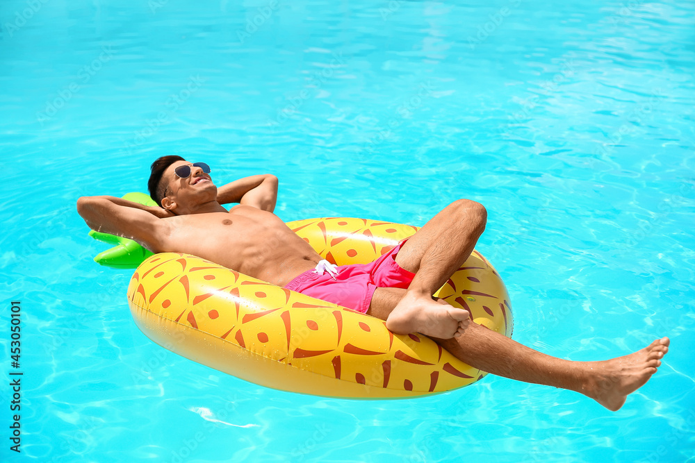 Handsome man with inflatable ring in swimming pool