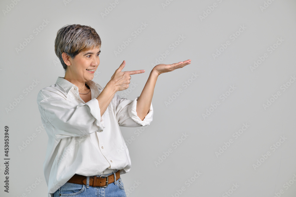 Middle aged Asian woman showing empty copy space on the open hands palm for text or product isolated