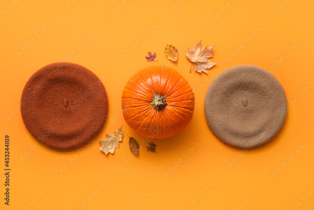 Composition with stylish berets and pumpkin on color background