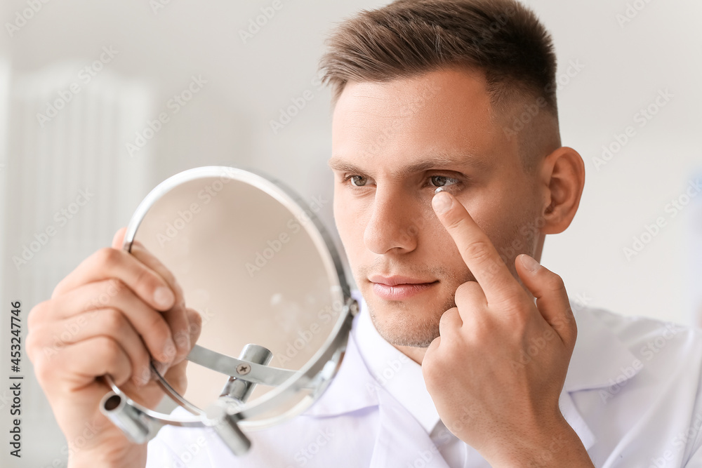 Young man putting in contact lenses