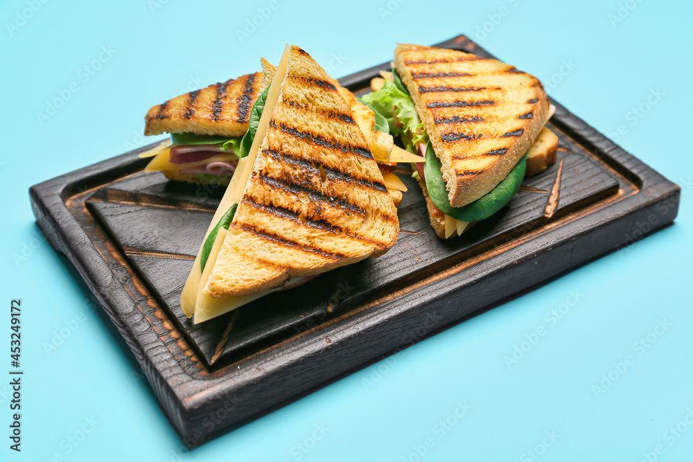 Board with tasty sandwiches on color background, closeup