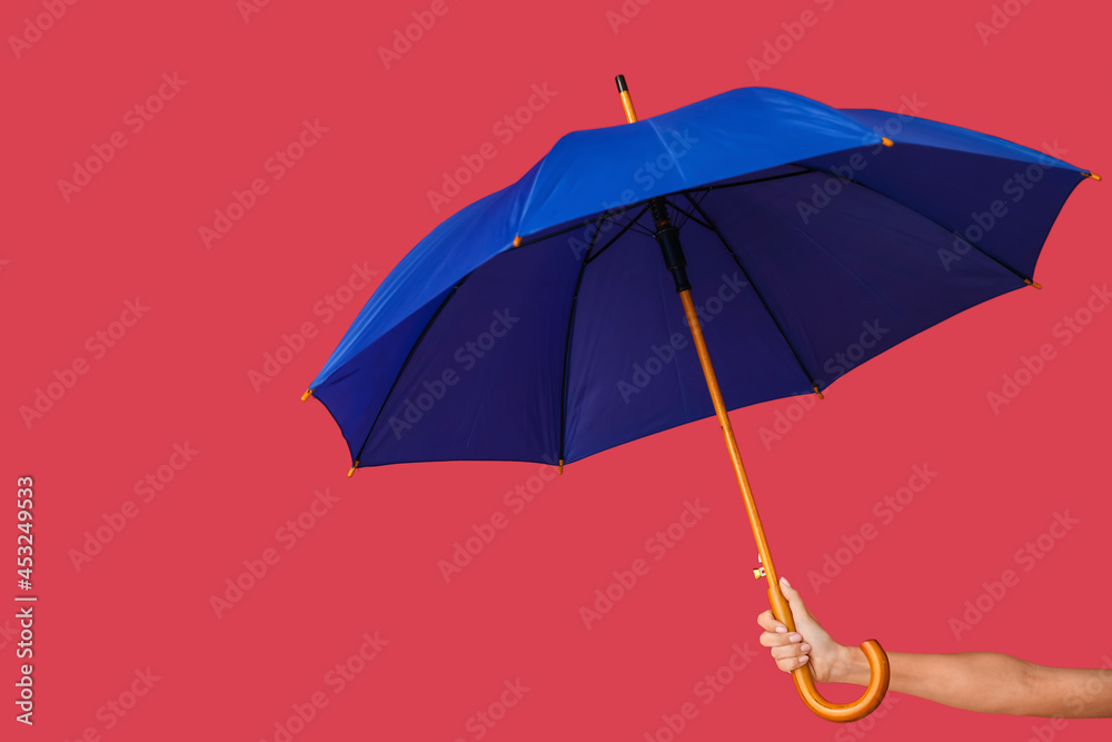 Female hand with open umbrella on color background