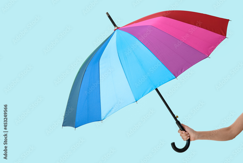 Female hand with open umbrella on light background