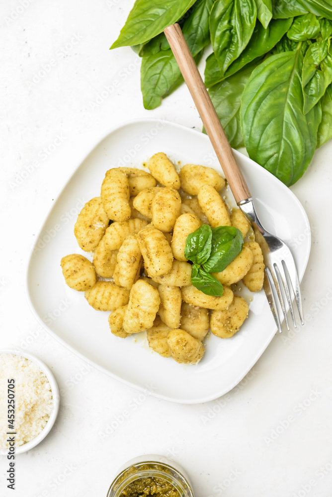 Composition with tasty pesto gnocchi on light background