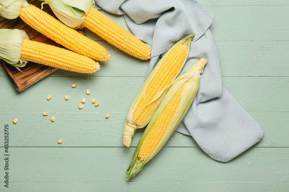 Fresh corn cobs on color wooden background