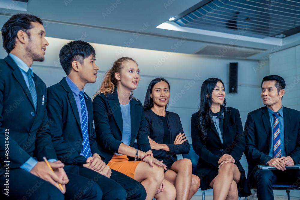 年轻的亚洲和高加索观众坐在那里听演讲人在小组会议上的演讲