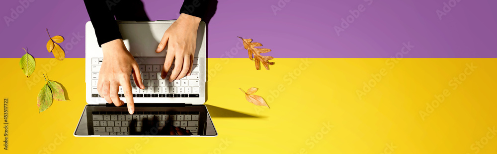 Autumn leaves with person using a laptop computer