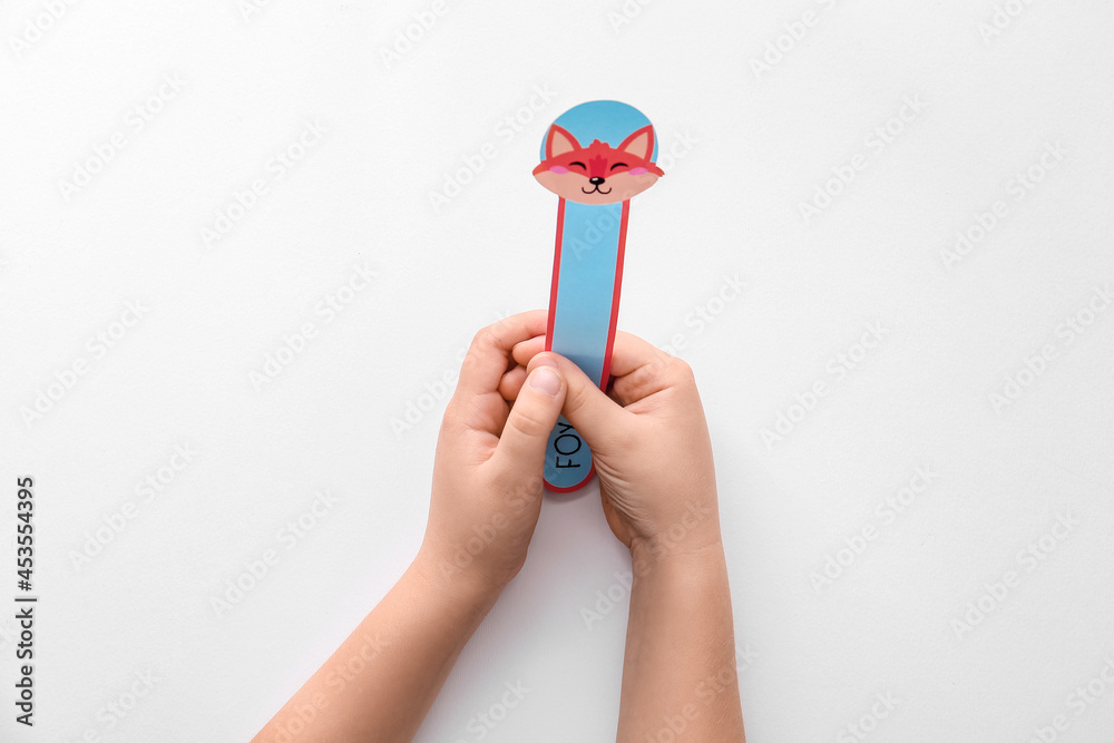 Hands of child with cute bookmark on white background