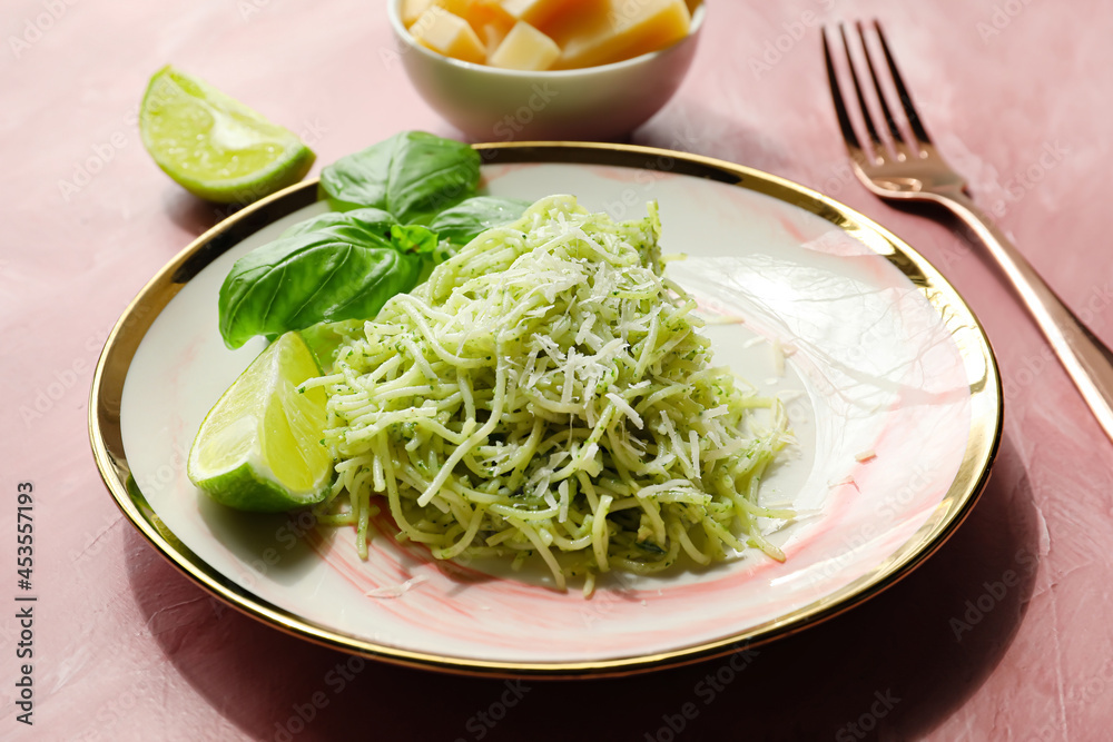 Plate with tasty pesto pasta and lime on color background, closeup