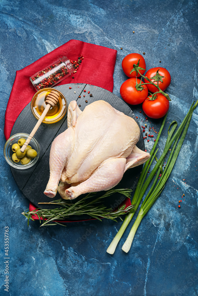 Board with whole raw chicken, honey, spices and vegetables on color background