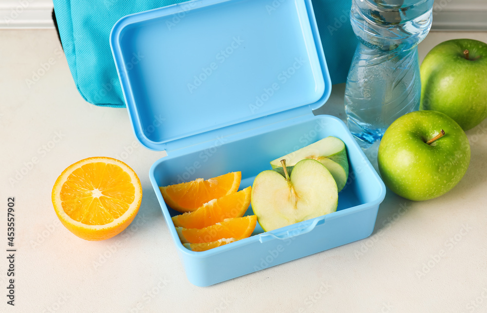 Lunch box with fruits on light background, closeup