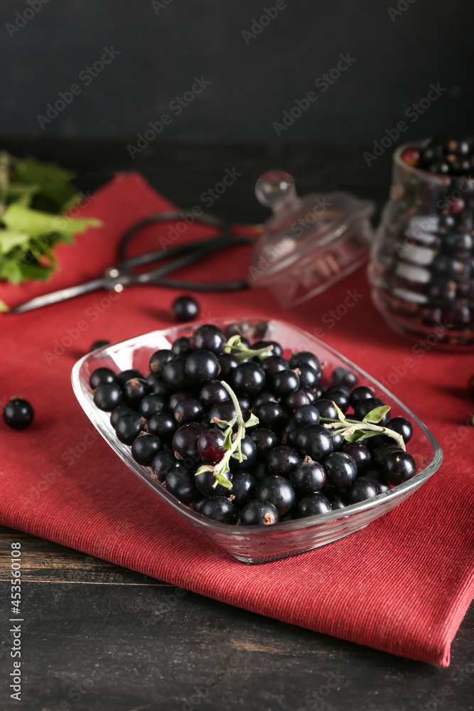 Bowl with ripe black currant on table