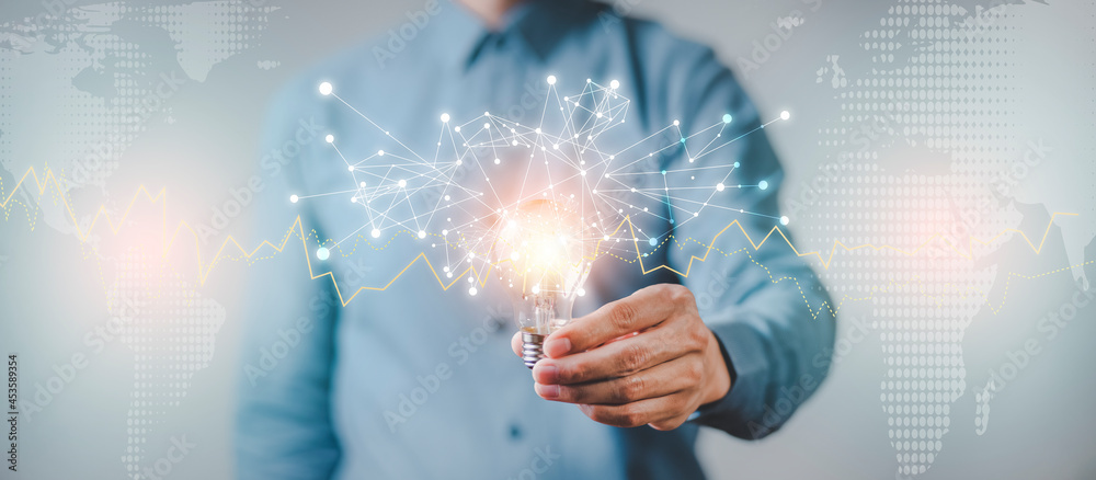 The Man hand holding light bulb with line connect and working on the desk, Creativity and innovation