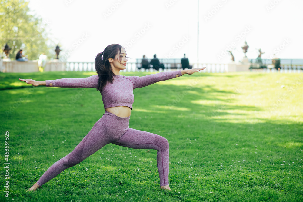 年轻的亚洲女性在自然公园做瑜伽健身运动，锻炼身体或热身