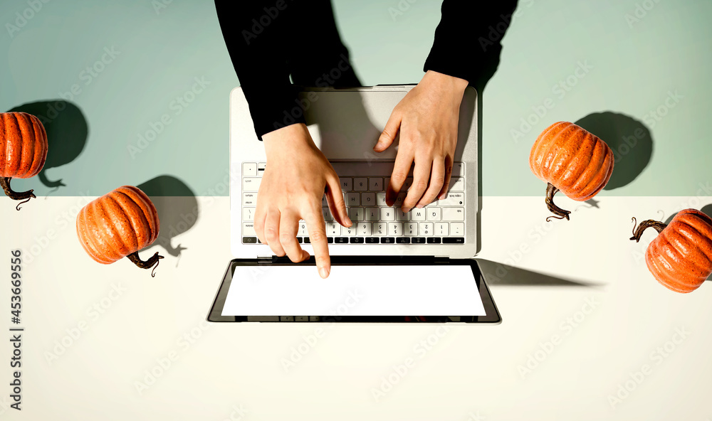 Autumn pumpkins with person using a laptop computer