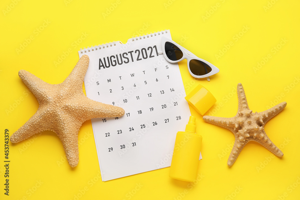 Calendar with beach accessories on color background