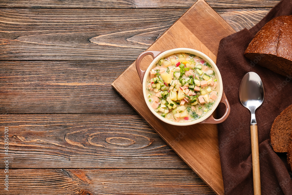 Cooking pot with tasty okroshka on wooden background