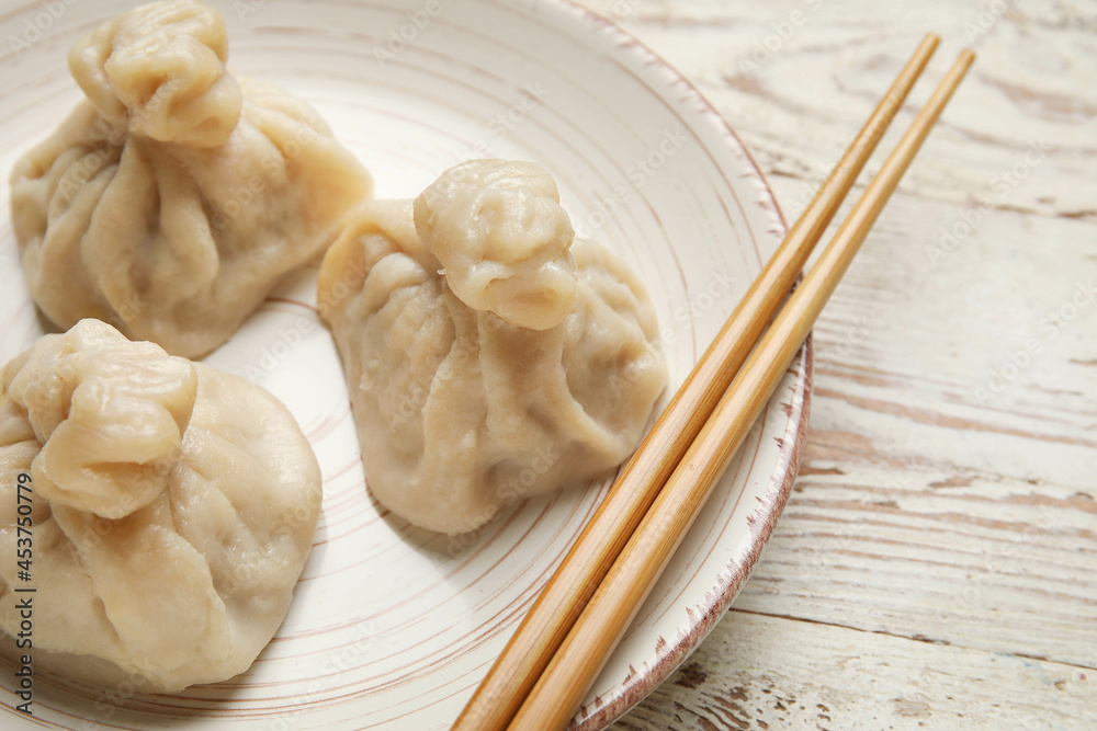 浅木背景下的盘子里有美味的饺子和筷子，特写