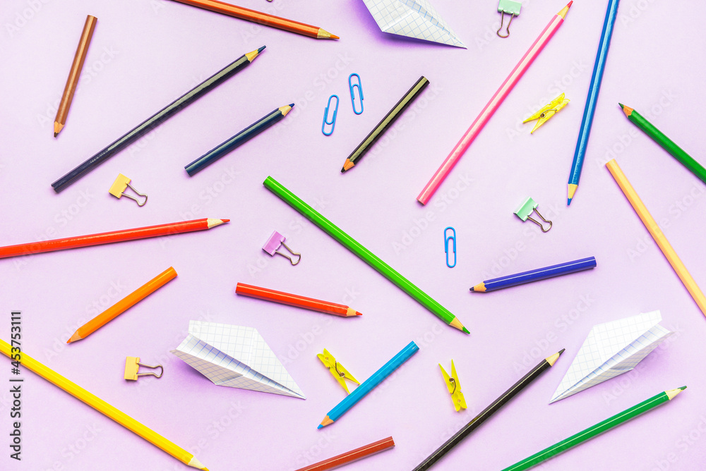 Paper airplanes with pencils and clips on color background