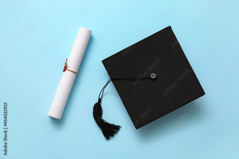 Graduation hat and diploma on color background