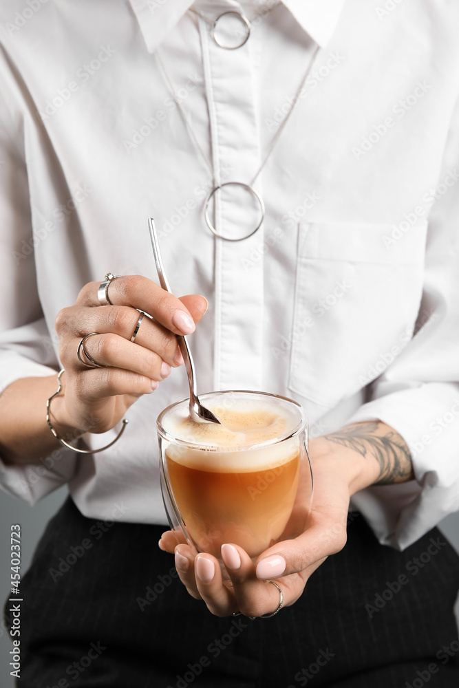 Woman drinking tasty coffee on grey background, closeup