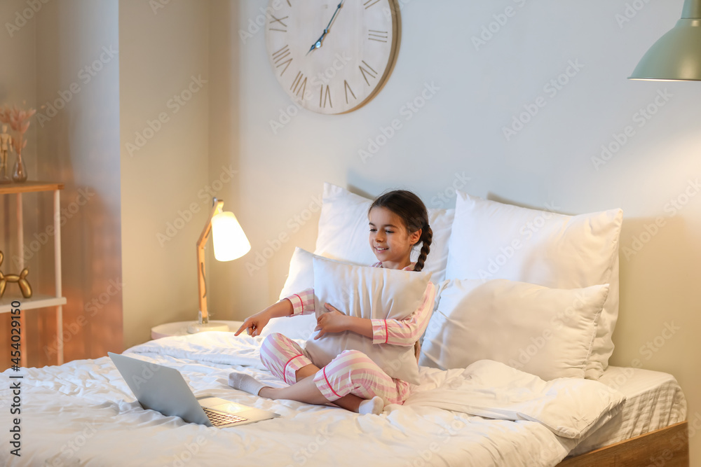 Cute girl watching cartoons in bedroom